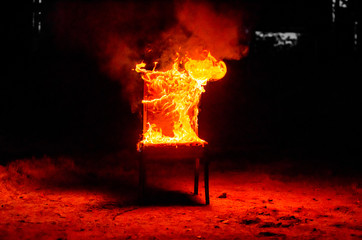 Wooden chair is on fire. Incineration of furniture. Conceptual photo, burnout