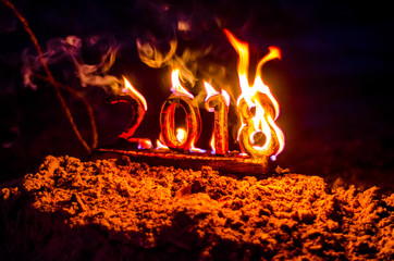 Wooden figures 2018 are burned in a flame. Conceptual photo end of the year.