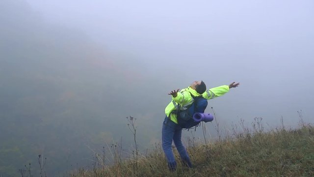 Man tourist with backpack climbed the mountain and screams with joy waving his hands,slow mo