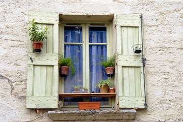 Fototapeta na wymiar Ville de Pézenas, fenêtres et volets verts, pots de fleurs posés sur le bord, département de l'Hérault, France