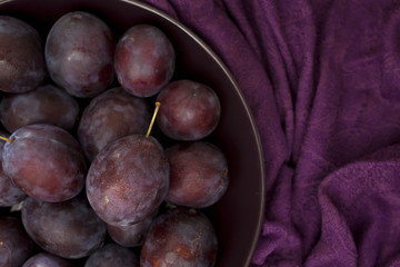 Ripe plums on a plate - dark purple composition