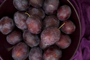 Ripe plums on a plate - dark purple composition