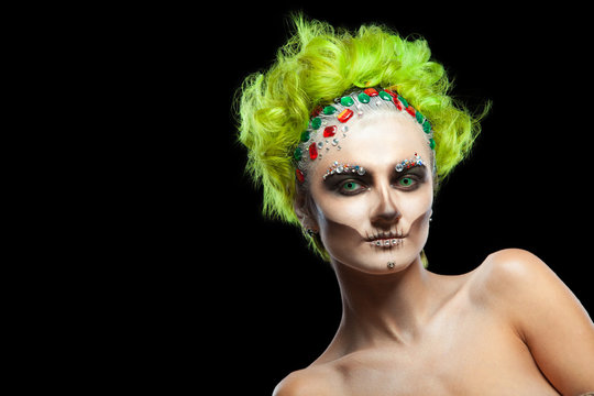 Halloween. Portrait of young beautiful girl with make-up skeleton on her face. And green hair. Isolated on black background.