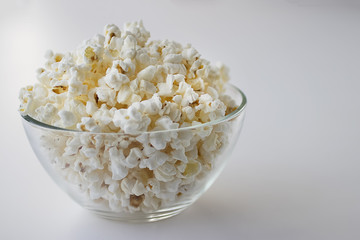 Popcorn in glass bowl on white background.