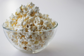 Popcorn in glass bowl on white background.