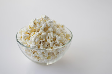 Popcorn in glass bowl on white background.