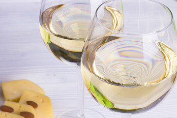 Glass of white wine with snacks - various types of cheese, figs, nuts, honey, grapes on a wooden boards background