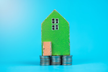 Model house with coins on color background. Concepts saving money for Home.