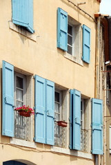 Fototapeta na wymiar Ville de Pézenas, façade d'une maison avec volets bleus ouverts et fleurs, département de l'Hérault, France