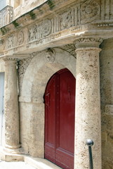 Ville de Pézenas, porche sculpté avec colonnades et porte rouge, département de l'Hérault, France
