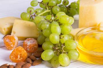 Cheese cuts with figs, nuts, honey, grapes on a wooden boards background