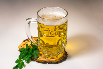 A mug of beer, green parsley on a wooden stand on a light background.