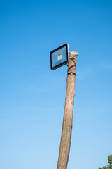 led street lamp mounted on a wooden tree trunk against a blue sky