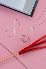 Silver jewelery, rings and bracelets minimalistic style on a pink background