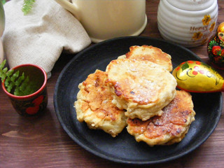 Russian cuisine : crepes pancakes on black cast iron with oak flakes on  wooden background with rustic milk jug and nesting dolls matrioshka close up