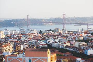 Beautiful super wide-angle aerial view of Lisbon, Portugal with harbor, skyline, scenery beyond the city and 25 de Abril Bridge, over the Tagus river, shot from belvedere observation deck