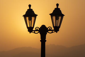 A silhouette of a lantern with the Ras al Khaimah mountains in the background at sunrise
