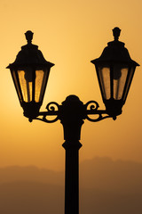 A silhouette of a lantern with the Ras al Khaimah mountains in the background at sunrise