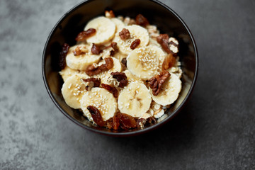 Healthy breakfast concept with oatmeal porridge with bananas,  nuts, raisins, sesame seeds  Top view. Super food. Food made of granola and musli.