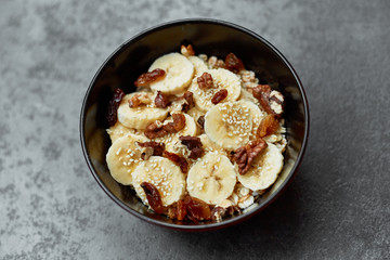 Healthy breakfast concept with oatmeal porridge with bananas,  nuts, raisins, sesame seeds  Top view. Super food. Food made of granola and musli.