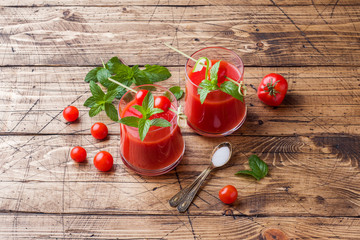 Tomato juice with mint in glass and fresh tomatoes on a wooden table. Healthy organic food concept