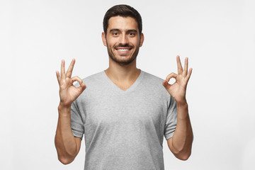 Handsome young smiling man showing okay sign with two hands