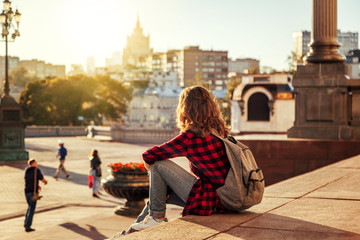 Beautiful woman in the background of a European city in the sun at sunset, student and traveler,...