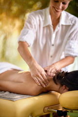 Close up of relaxed woman receiving a massage in a spa in nature.