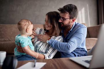 Happy family-man and woman spending happy time at home with their baby son and playing together.