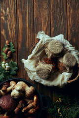 top view of delicious pickled mushrooms in basket and fresh mushrooms in pan on wooden table