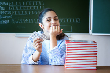 Student with piils sits near blackboard in classroom