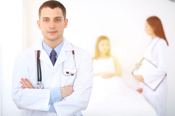 Fototapeta premium Medicine doctor standing and smiling on the background with patient in the bed