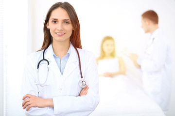 Fototapeta premium Medicine doctor standing and smiling on the background with patient in the bed