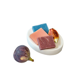Small pieces of natural soap in a soap tray and a ripe juicy figs  on a white background. 