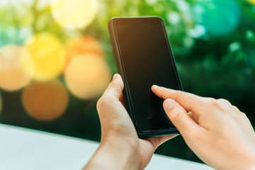 Woman hand using smartphone and laptop with cafe shop sunlight  shade to object beautiful background.