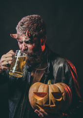 Halloween man with satan horns hold pumpkin