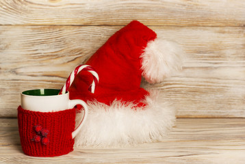 Obraz na płótnie Canvas Santa hat and cup on Christmas background
