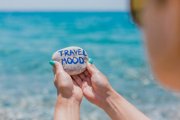 Girl holding round stone with sign about travel theme