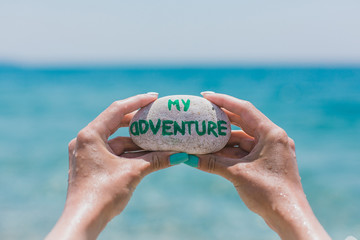 Girl holding round stone pebble with sign about travel theme