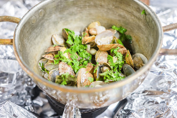 Clams with garlic and coriander in copper pot