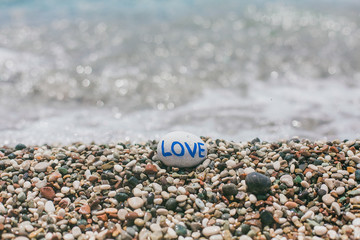 Round stone pebble with love on a beach.