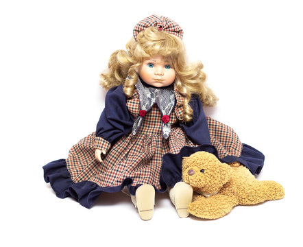 Old porcelain doll on White Background, ceramic dolls and a teddy bear.