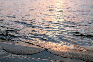 Waves on beach at sunset.