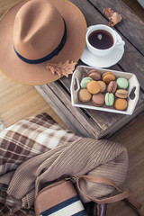 Fototapeta na wymiar A cup of hot tea, macaroons, a knitted sweater, a hat, a rug on a wooden table. Autumn. Winter. Cozy.