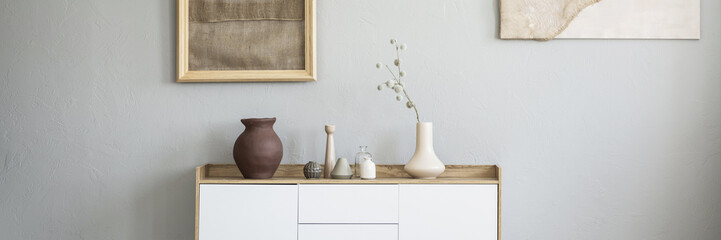 Panorama of earth tone color, clay and ceramic vases on a wooden, white cabinet in a natural living room interior