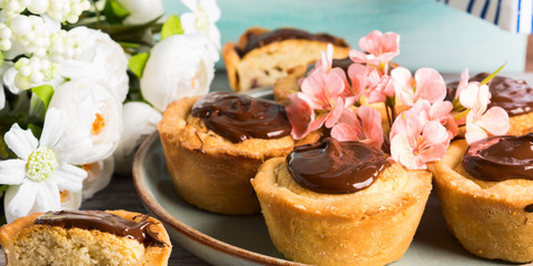 Cakes with frangipane, cherry jam and chocolate frosting. Romantic table setting with flowers. Mother's day card
