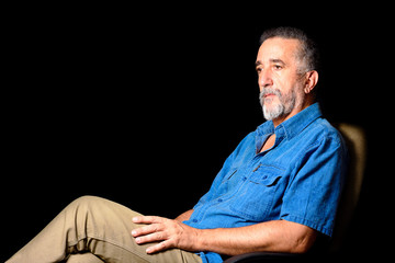 Fototapeta premium Portrait of adult man seated on black background