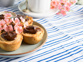 Cakes with frangipane, cherry jam and chocolate frosting. Romantic table setting with flowers. Mother's day card