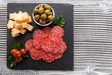 delicious sliced salami on a stone plate wooden background