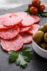 delicious sliced salami on a stone plate wooden background